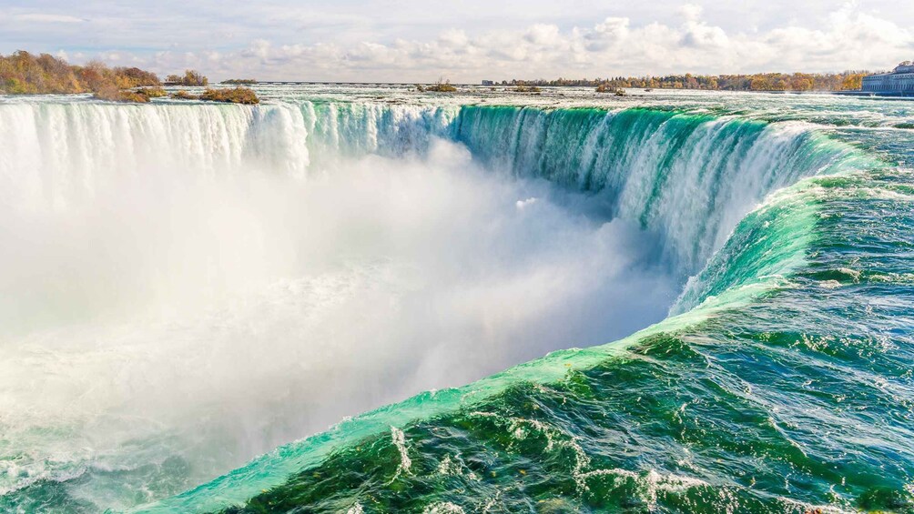 A large waterfall with a wide, foamy base and a clear sky in the background. 3