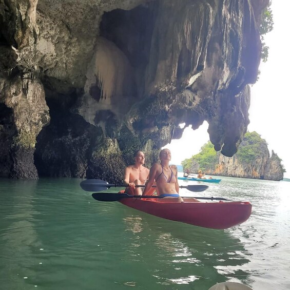 Two people kayaking in a cave opening with water. 1