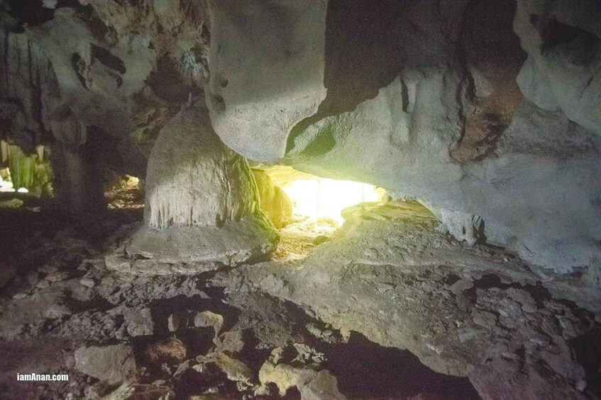 A cave interior with stalactites and a light source at the bottom. 5