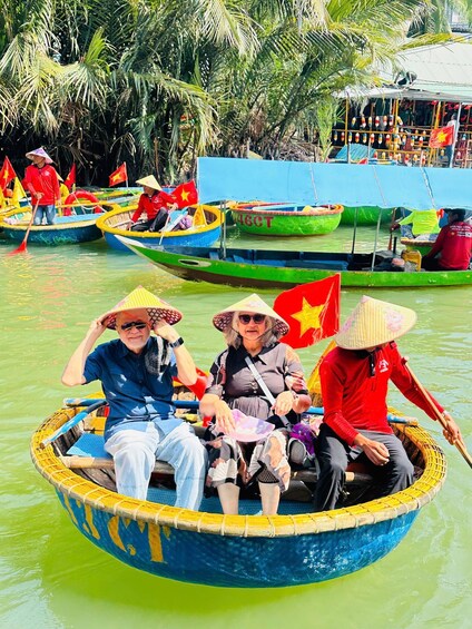 Un groupe de personnes se trouve dans un bateau traditionnel arborant le drapeau vietnamien, entouré d’autres bateaux aux couleurs vives et de palmiers. 5