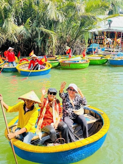 Un groupe de personnes se trouve dans un bateau traditionnel sur une rivière, entouré d’autres bateaux aux couleurs vives et de palmiers. 1