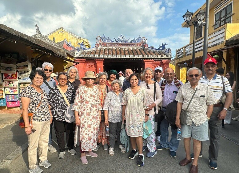 Un groupe de personnes se tient devant un bâtiment traditionnel à l’architecture richement décorée. 4