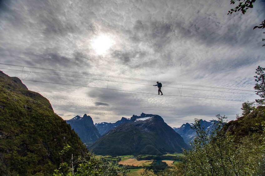 A person walking on a suspended cable between mountains. 2