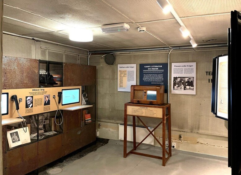 A museum exhibit with historical artifacts, including a wooden radio, a computer, and informational posters on the walls. 3