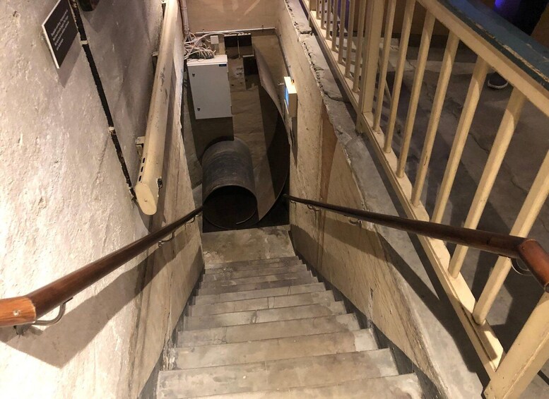 A staircase with metal railings and a cylindrical object at the bottom. 2