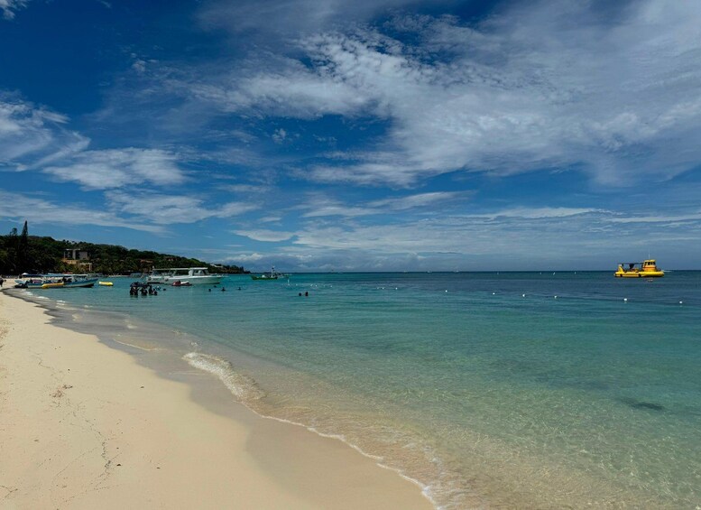 A beach with clear turquoise water, a sandy shore, and a few boats. 3