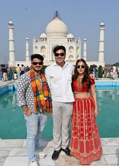 Tre personer står framför Taj Mahal, med en pool i förgrunden. 1
