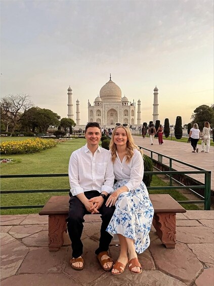Ett par sitter på en bänk med Taj Mahal i bakgrunden. 2