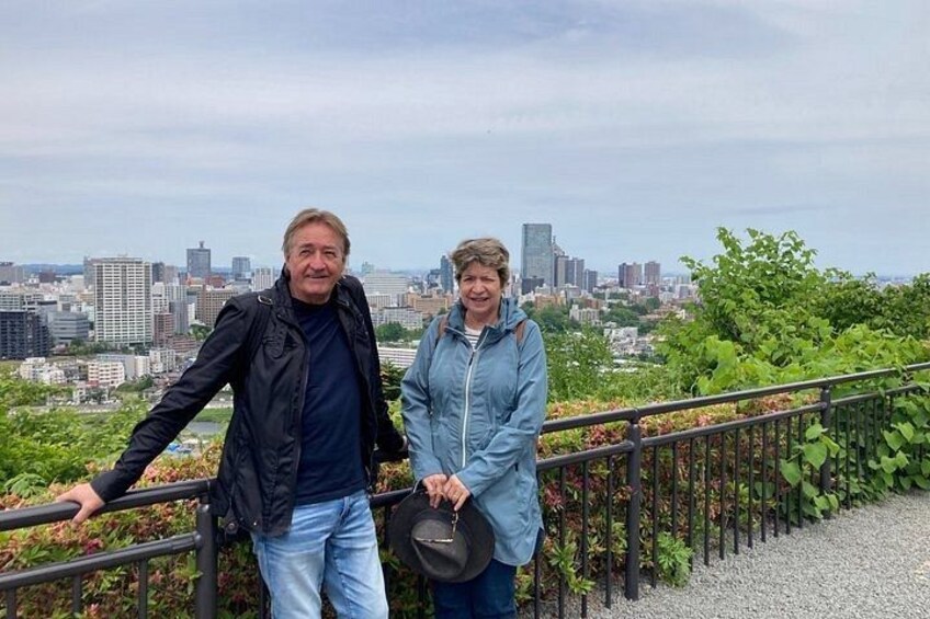 Two people standing on a railing with a cityscape in the background. 4