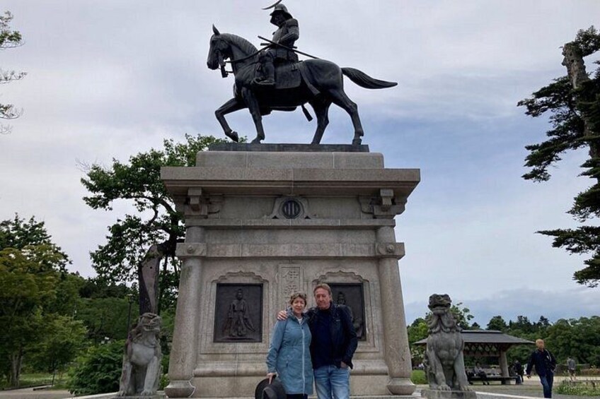 A statue of a mounted figure on a pedestal with two people standing in front. 5