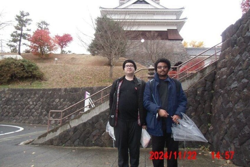 Two people standing in front of a traditional Japanese building with a stone staircase. 2