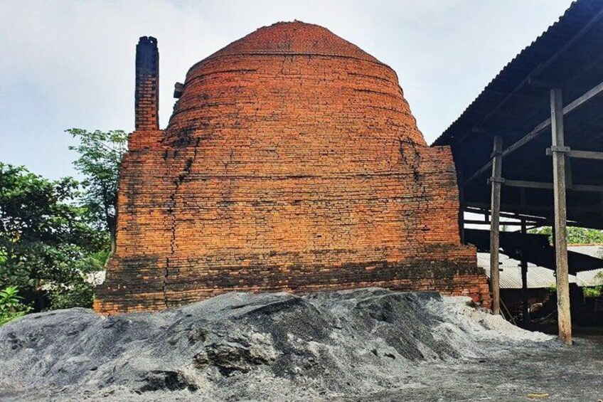 A brick structure with a dome roof, a chimney, and a pile of sand in front. 3