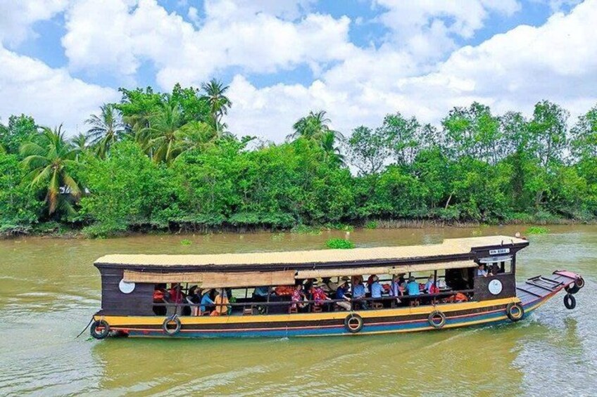 A riverboat with passengers, surrounded by lush greenery and palm trees. 2