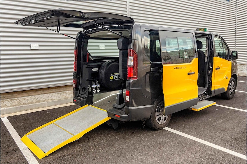 A yellow and gray van with an open back door and a ramp attached to the rear. 3