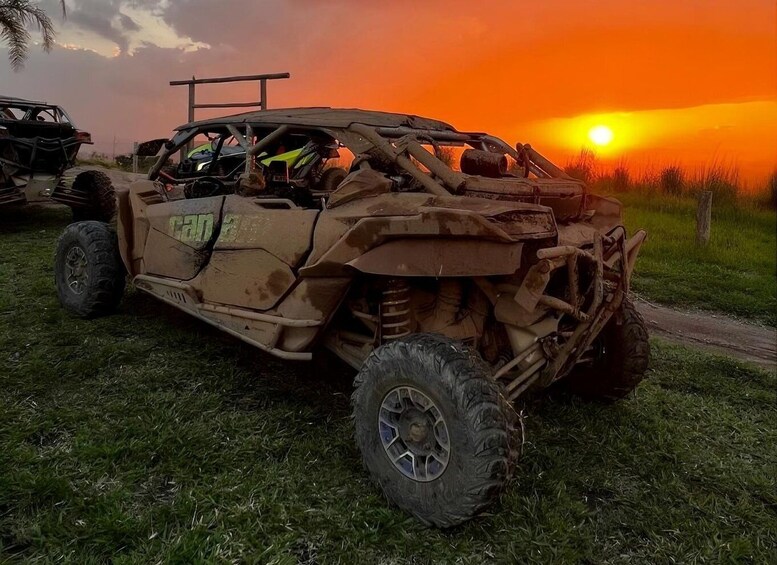 A yellow off-road vehicle parked on grass with a sunset in the background. 2
