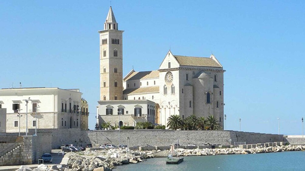 A coastal church with a prominent tower and a clock tower, surrounded by a rocky breakwater and calm water. 4