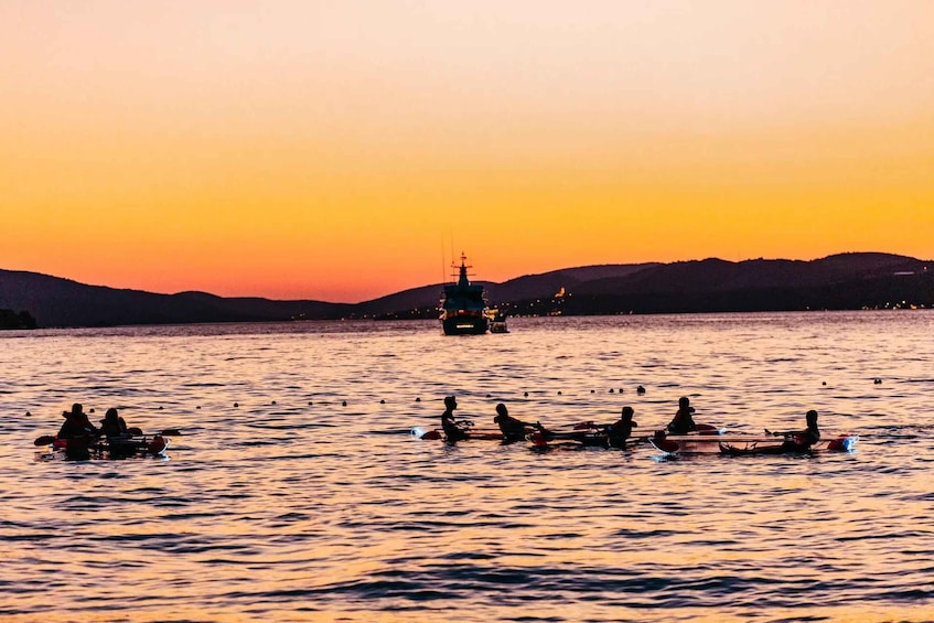 A sunset over a body of water with boats and a ship in the distance. 2