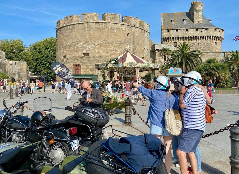 A historical castle, a carousel, and people in a public square. 4
