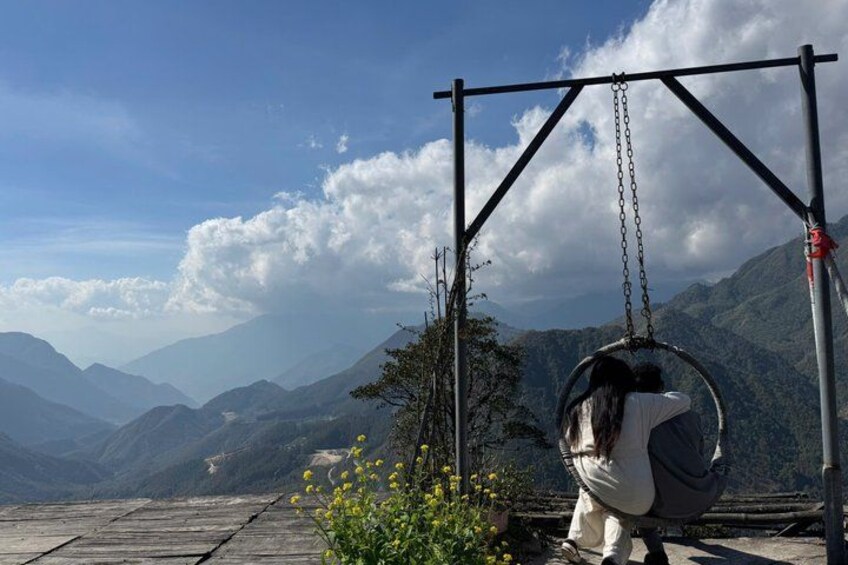 A person on a swing overlooking a mountainous landscape. 5