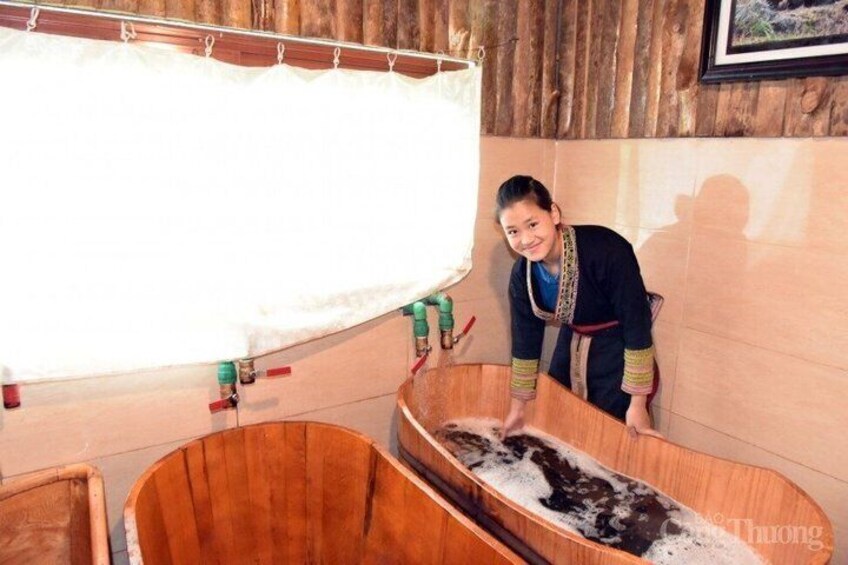 A wooden bathtub filled with water and soap, a person in traditional attire, and a wooden wall with a curtain. 4