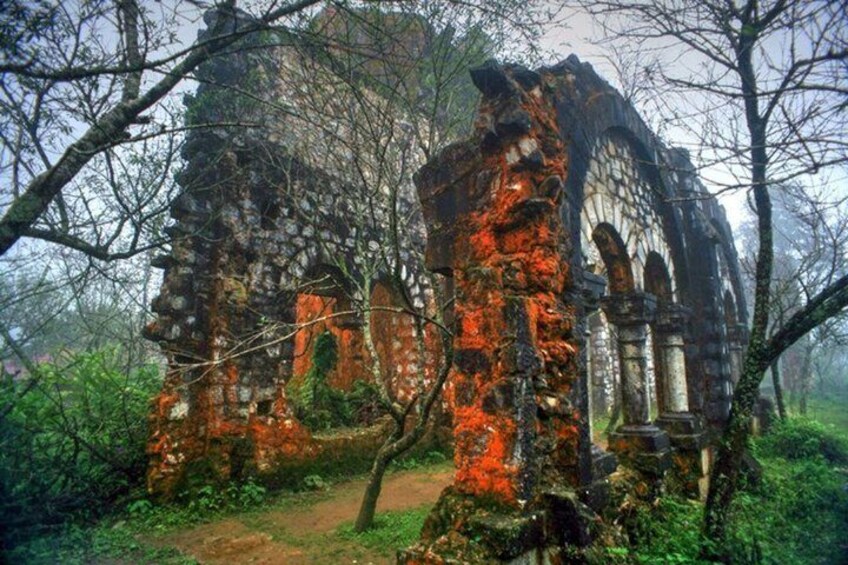 A dilapidated stone structure with arches and columns, surrounded by trees and vegetation. 5