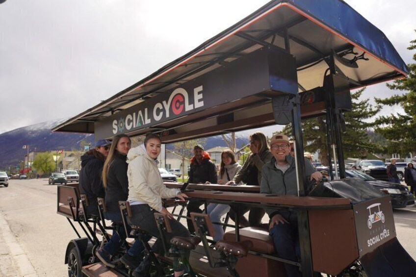 A group of people on a stationary bicycle with a canopy labeled 'SOCIAL CYCLE.' 3