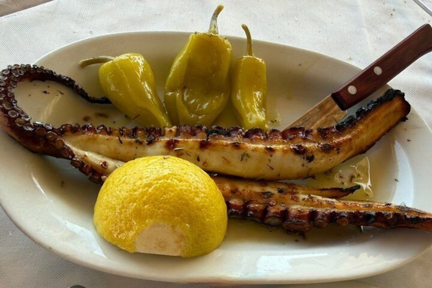 Grilled octopus, lemon, and green peppers on a plate. 5