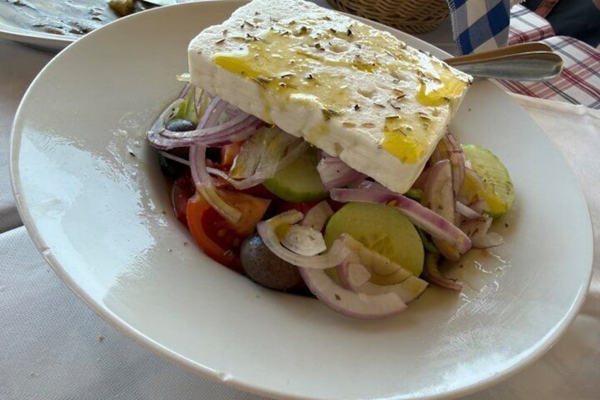 A plate of food with a piece of white cheese on top, surrounded by sliced vegetables. 3