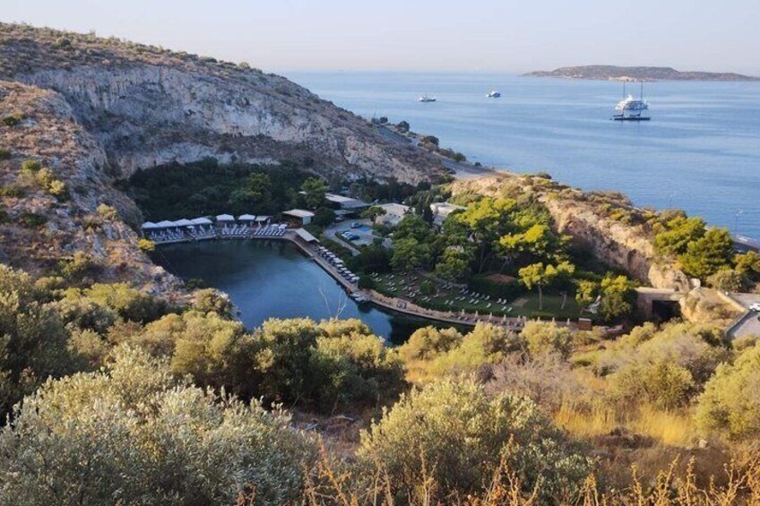 A coastal landscape with a rocky cliff, a marina with boats, and a small pier. 1