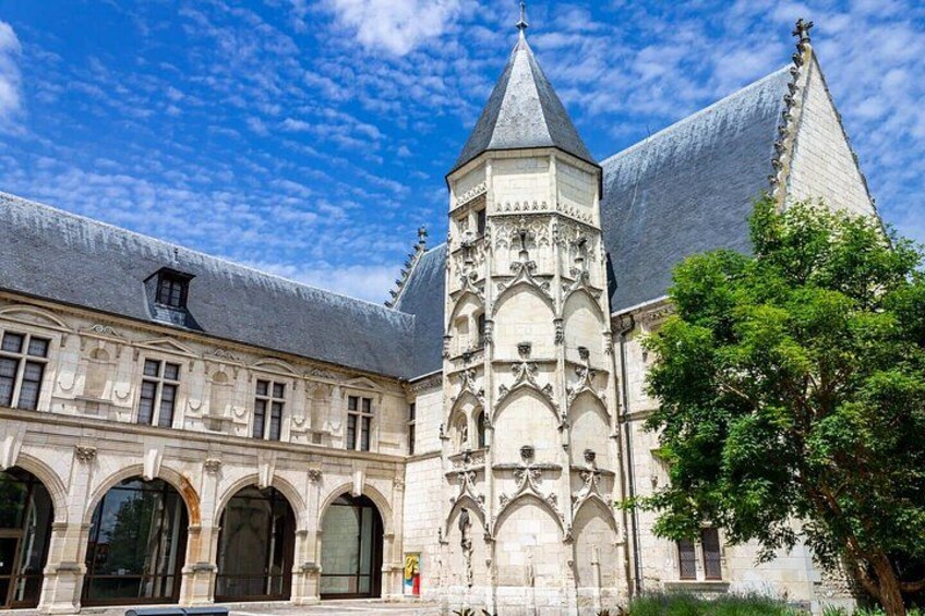 A historic building with a tower, arched windows, and a tree in the foreground. 4