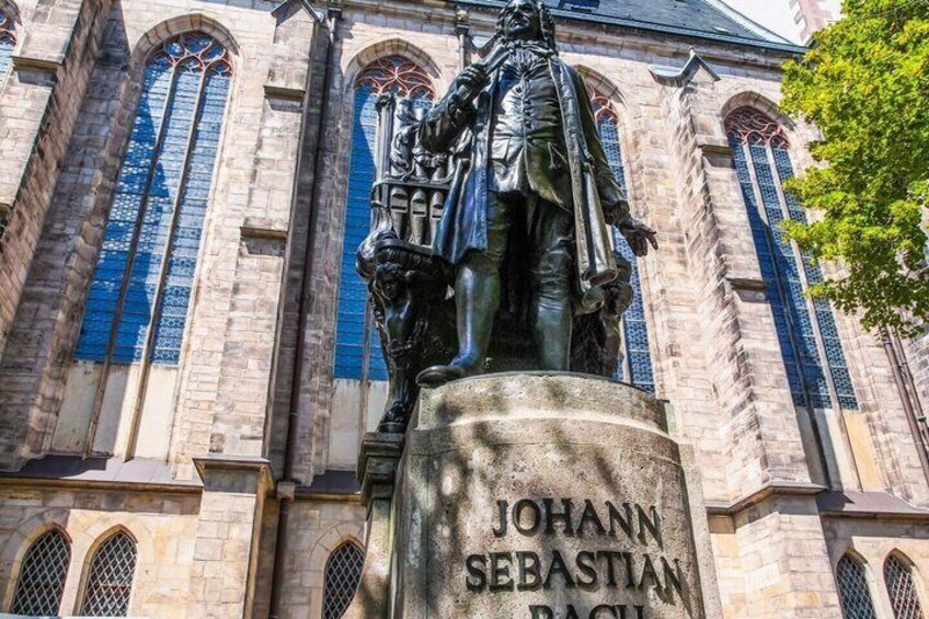 A statue of Johann Sebastian Bach in front of a historic building with arched windows. 2