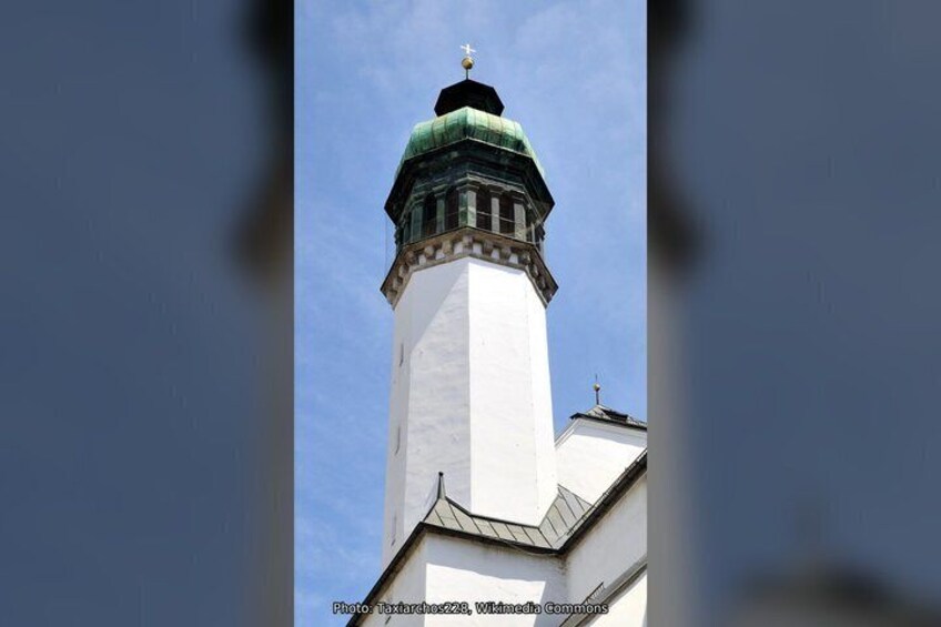 A white tower with a green dome and a cross on top. 4