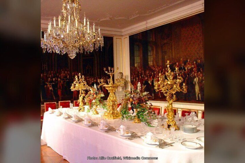 A banquet table with golden candelabras, white tablecloth, and red chairs. 5