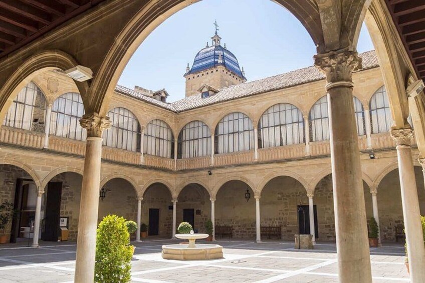 A courtyard with arches, a fountain, and a building with a blue dome in the background. 3