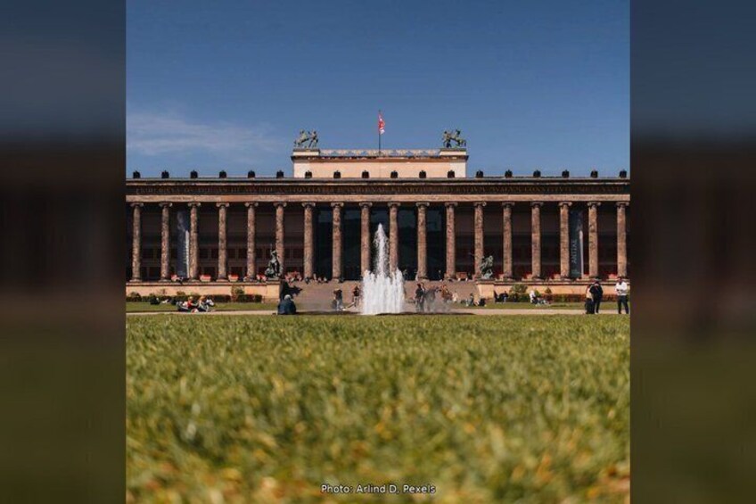 A large classical building with columns, a central fountain, and a flag on top. 5