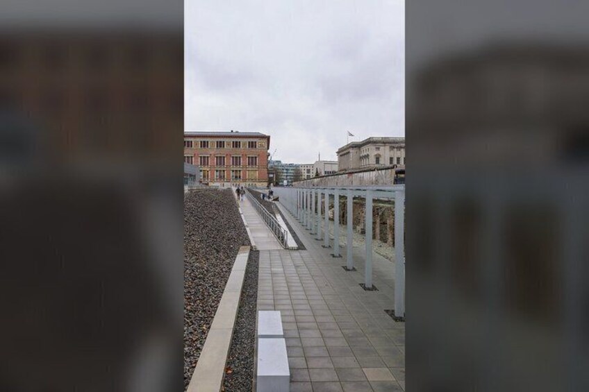 A pathway with a railing, a building in the background, and a cloudy sky. 3