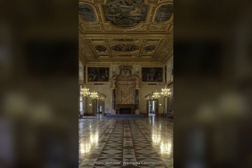 A grand hall with a high ceiling, ornate decorations, and a large fireplace. 4