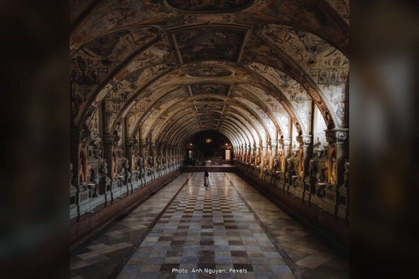 A long corridor with a checkered floor, arched ceilings with frescoes, and columns. 3