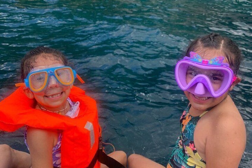 Two individuals in a body of water, wearing life jackets and snorkeling gear. 5