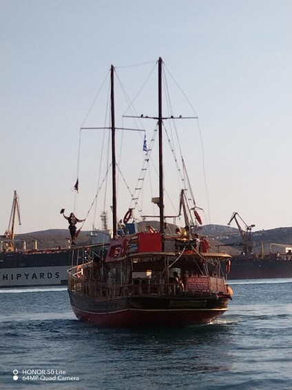 A ship with a flag, a person standing on the deck, and another person on a ladder. 3