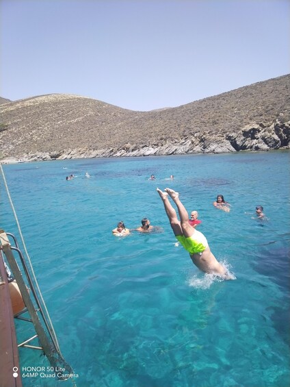 A group of people swimming in a clear blue pool with rocky hills in the background. 4