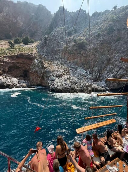 A group of people on a boat near rocky cliffs by a turquoise sea. 2