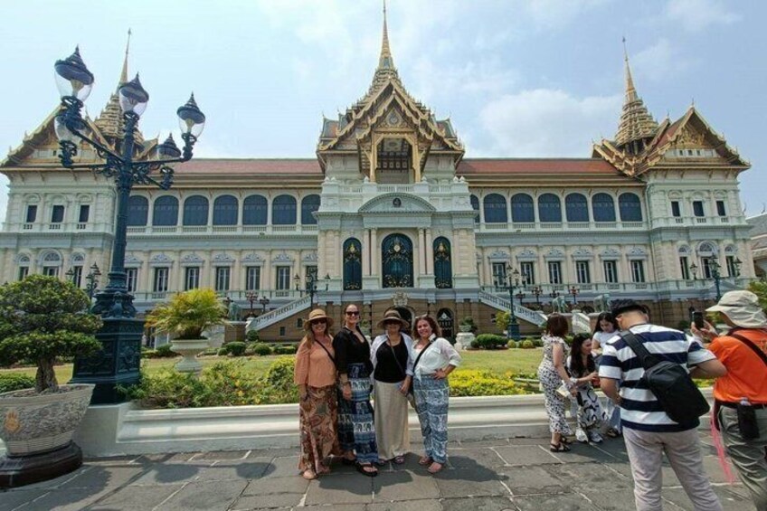 A group of people posing in front of a large, ornate building with a traditional architectural style, featuring multiple spires and a large central entrance. 4