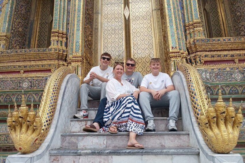 A group of people sitting on ornate steps with intricate golden decorations and statues. 1