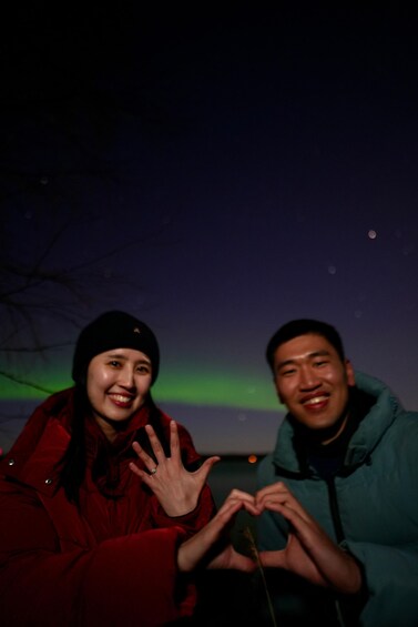 Two people making a heart shape with their hands against a night sky with visible stars. 4