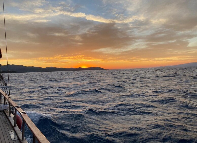 A sunset over the ocean with waves and a distant landmass. 5