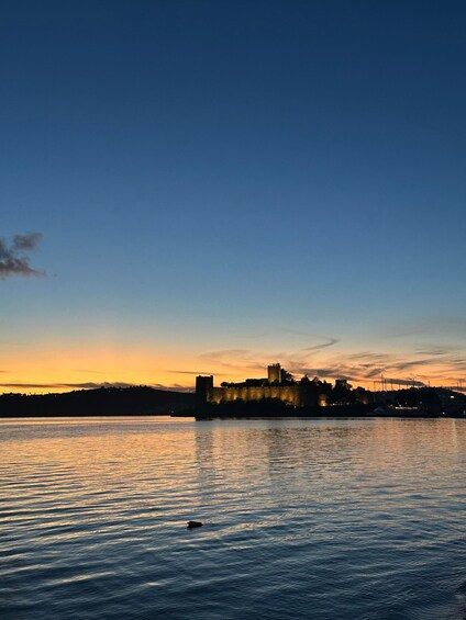 A sunset over a body of water with a castle silhouette on a hill. 3