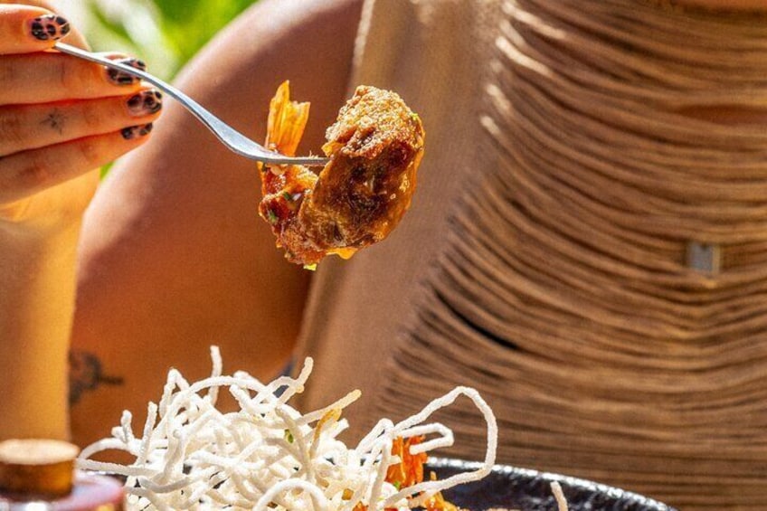 A person holding a fork with a piece of food, a bowl of noodles, and a plate with a drink. 3