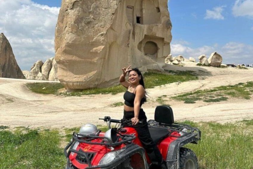 A person on a red ATV in a rocky landscape with large rock formations. 5