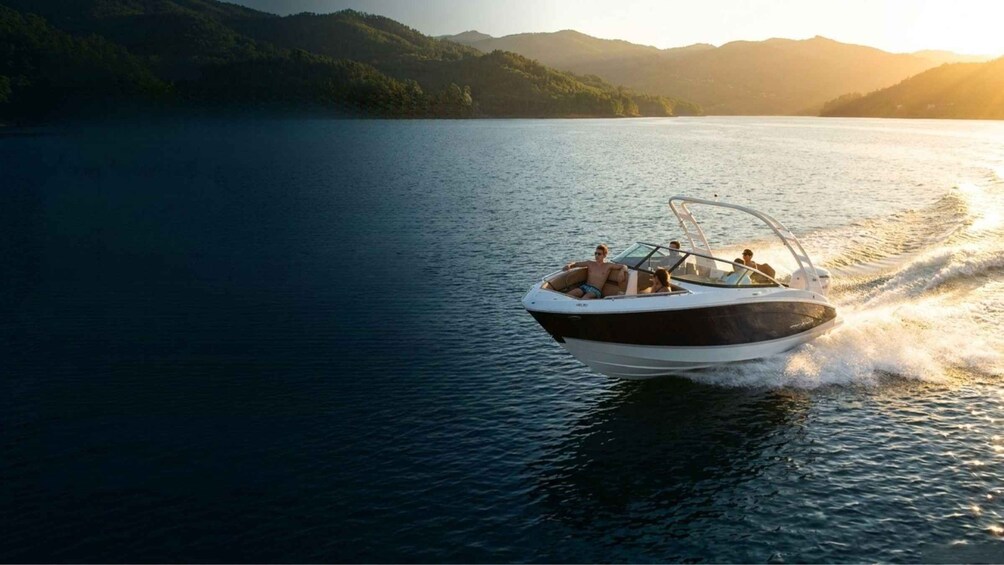 A motorboat on a calm lake with mountains in the background. 1